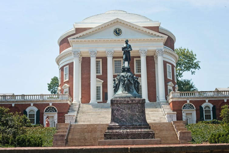 A statue of a man on a horse, in front of a round brick structure fronted by columns.