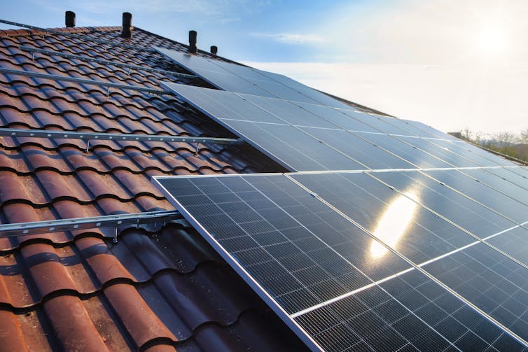 Solar panels are installed on a sloping house roof.