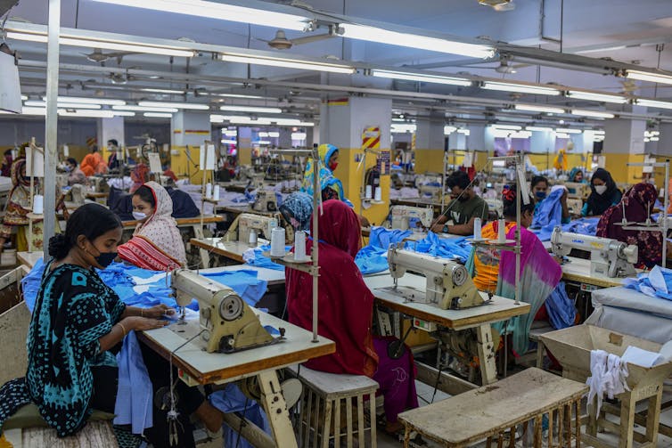 Workers, mostly women, at sewing machines in a factory.