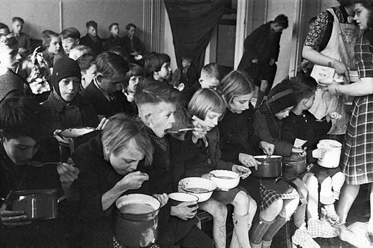Les enfants mangent dans des pots disposés en rangées.