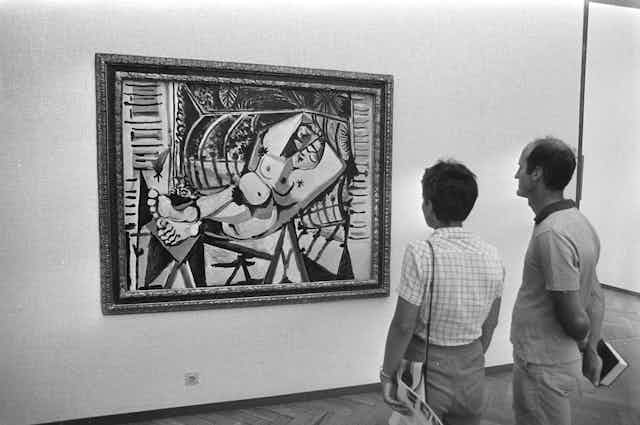 Un hombre y una mujer observan una pintura de Picasso.