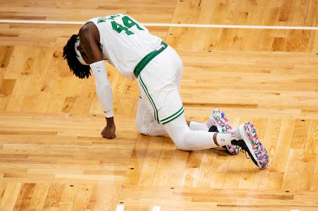 Injured basketball player crawls along parquet.