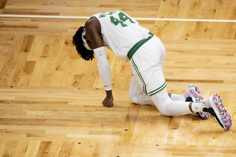 Injured basketball player crawls along parquet.