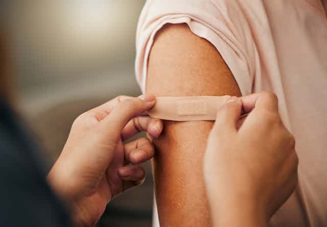 Immuniser puts a bandaid on a patient