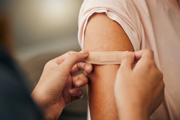 Immuniser puts a bandaid on a patient