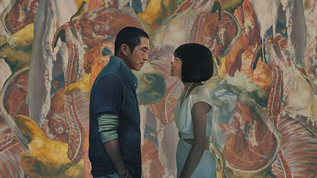 A man and a woman stare at each other in front of a graphic painting