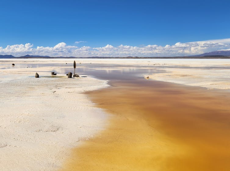 The pale expanse of a salt flat beneath a bright blue sky.