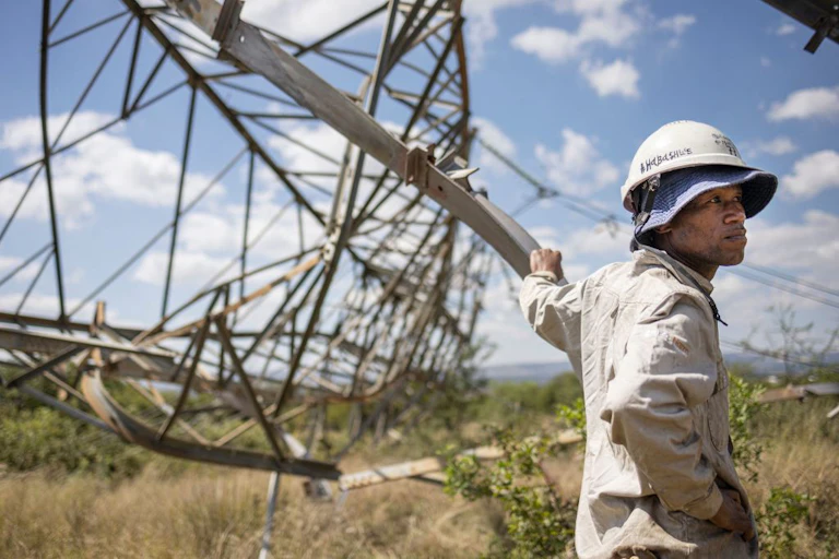 A worker leans on a collapsed pylon