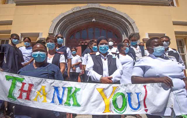 masked health workers standing in front of a hospital