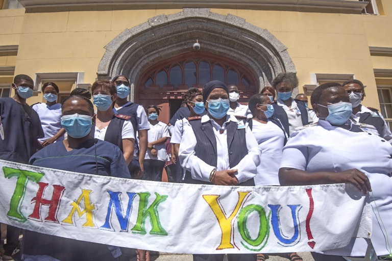 masked health workers standing in front of a hospital