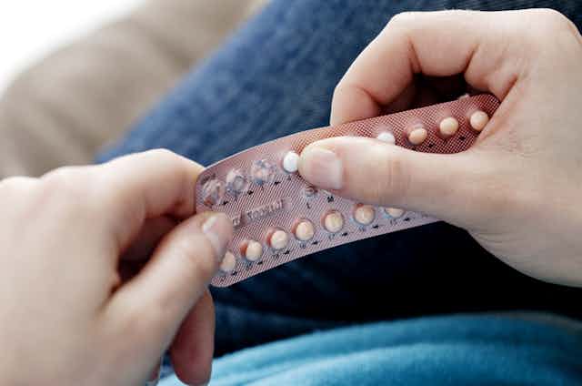 A woman holds a pack of birth control pills in her hands.