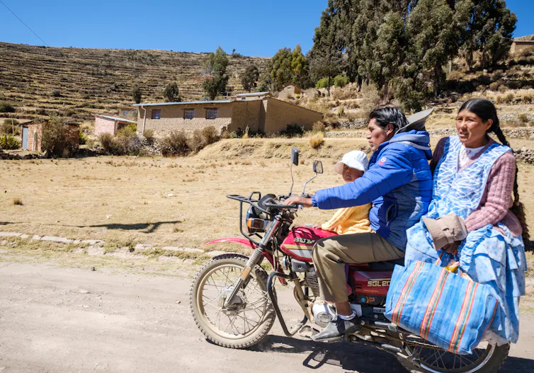 Mother, father and child sit on a motorbike.