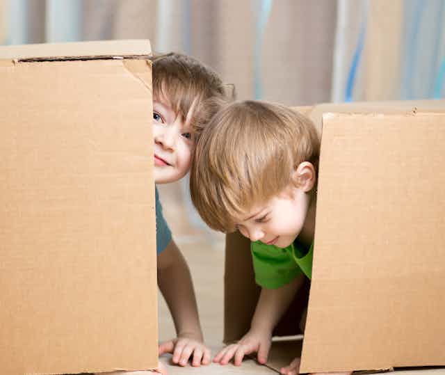 Two children seen inside a large box.