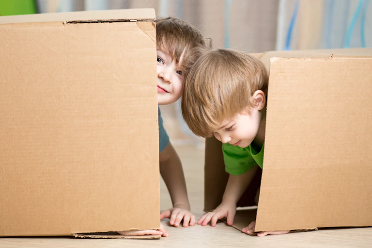 Two children seen inside a large box.