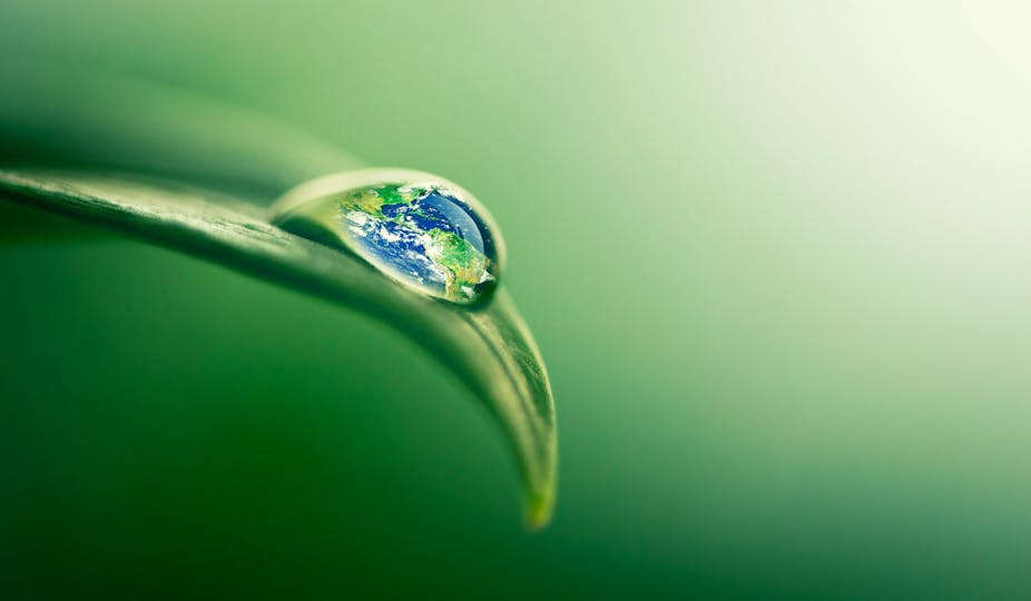 Concept image of planet Earth in a droplet rolling off a leaf