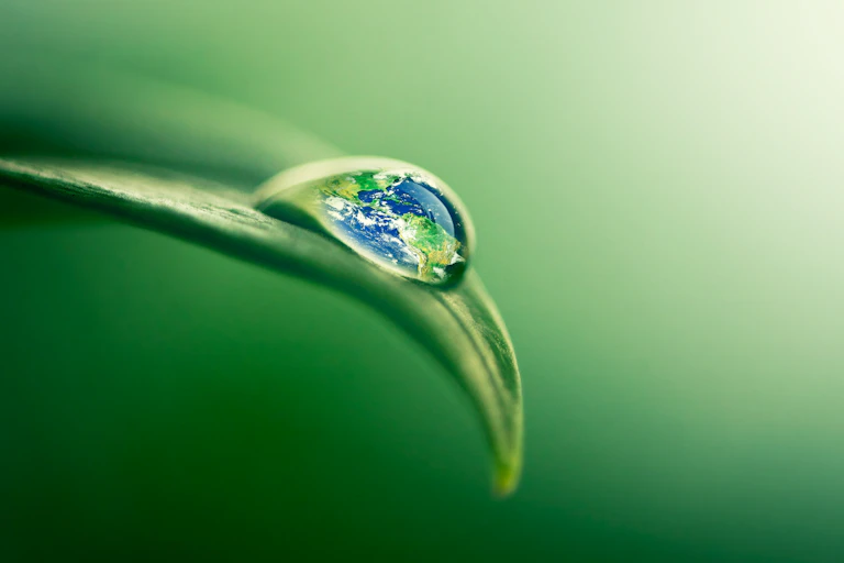 Concept image of planet Earth in a droplet rolling off a leaf