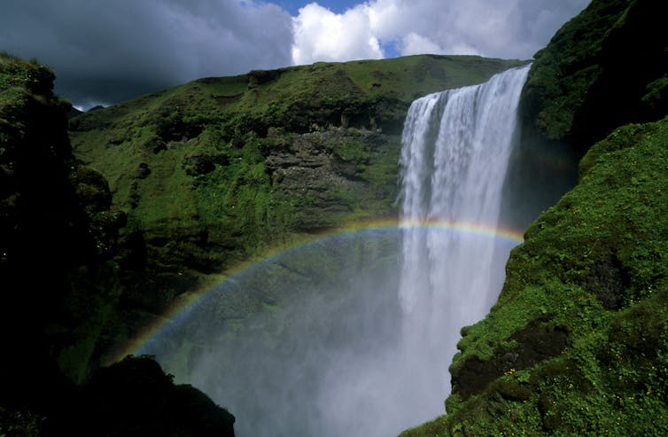 Un arco iris en la niebla debajo de una cascada en Islandia.