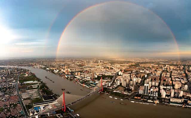 From a high view, a rainbow over a bridge in Shanghai is almost circular.