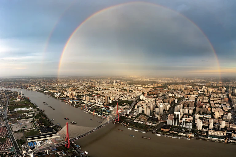 From a high view, a rainbow over a bridge in Shanghai is almost circular.