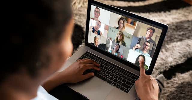 A person seen on a videoconference, looking at other participants' faces.