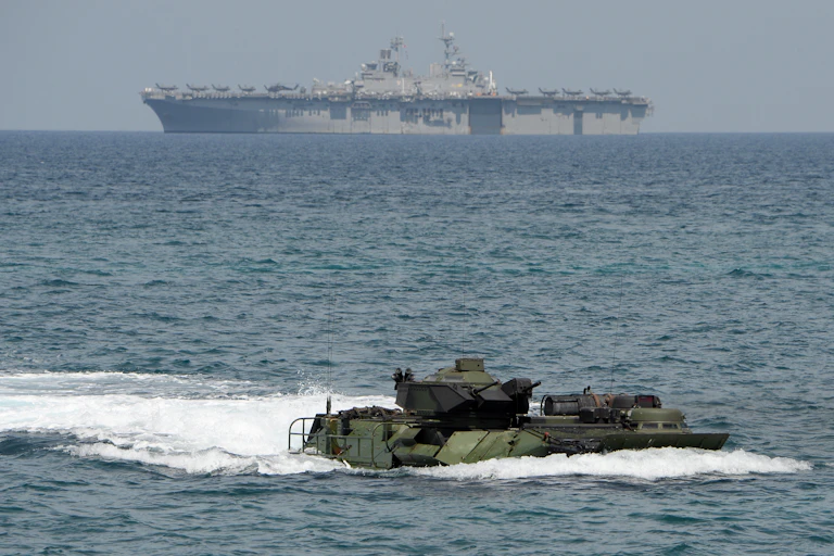 A small vessel in water is seen in the foreground while a huge aircraft carrier is seen in the background.