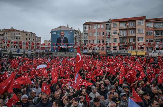 A large crowd of people waving Turkish flags at a rally