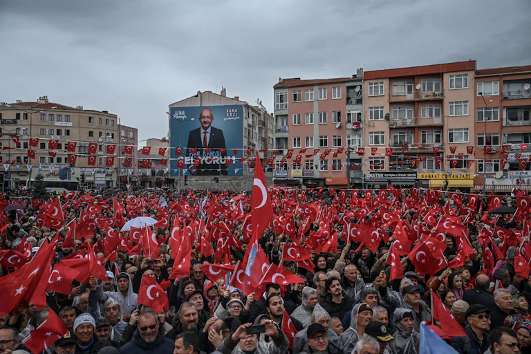 A large crowd of people waving Turkish flags at a rally