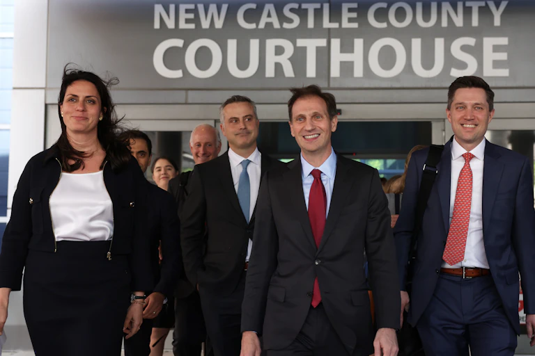 Suited men and women exit the New Castle County Courthouse together with broad smiles on their faces.