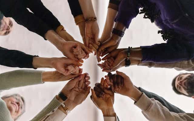 People stretching their arms together in a circle