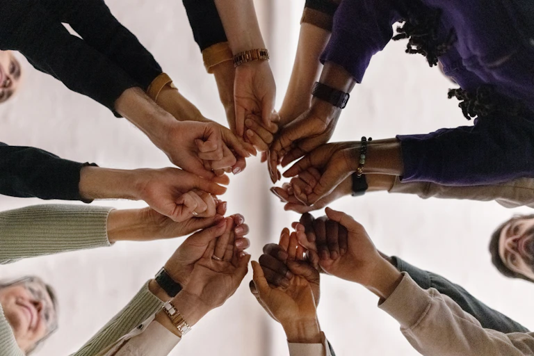 People stretching their arms together in a circle