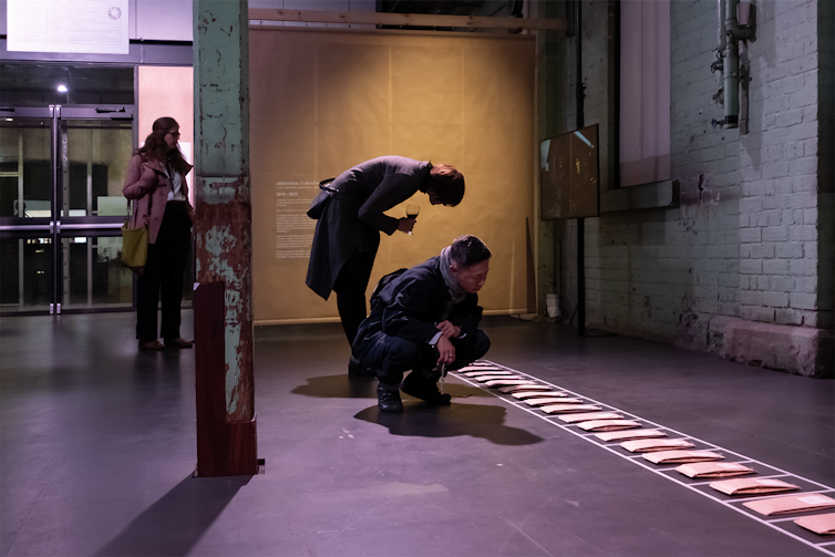 People look at envelopes in a line on the ground.