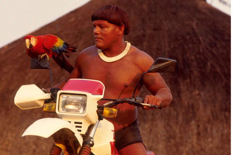Indigenous man on motorbike with parrot.