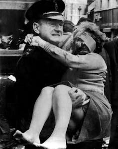A policeman carrying a woman with a bandage over her eye in the aftermath of a bomb.