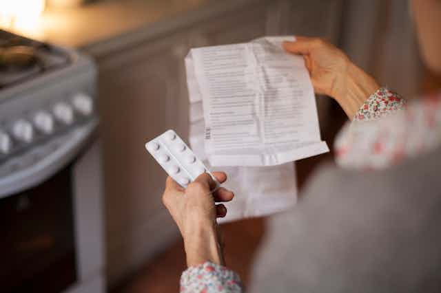 Person holding blister pack of pills reading package insert