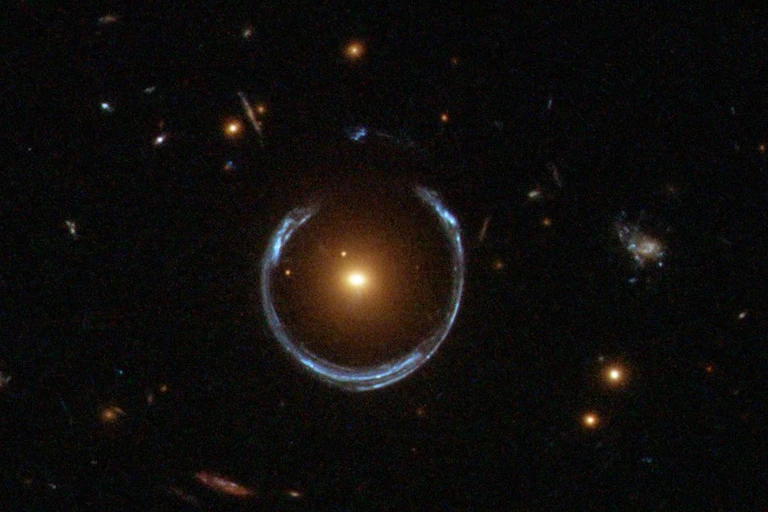 A photo showing an 'Einstein ring' of light around a bright central galaxy.