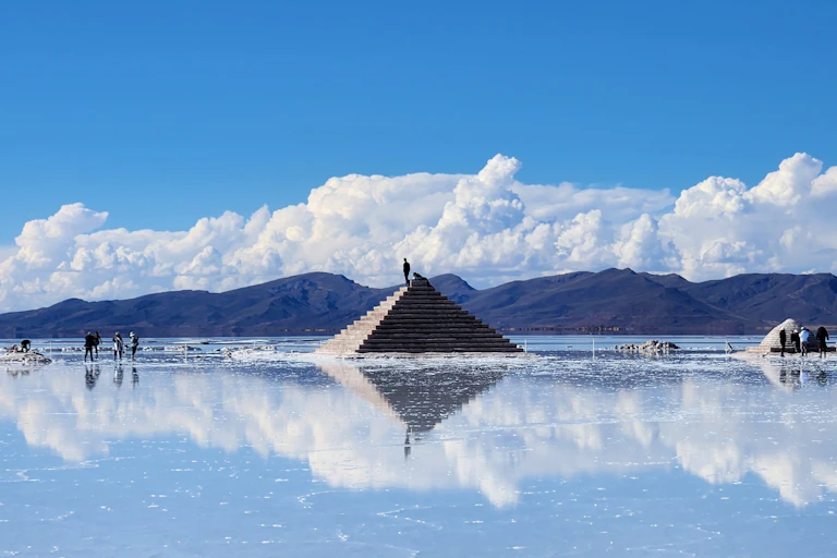 A sunny blue sky is reflected in the shallow water of a salt flat