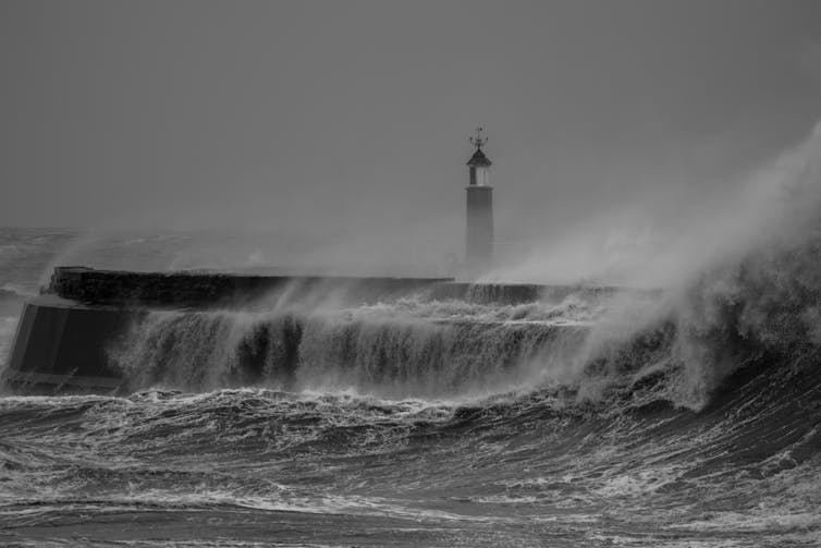 Uma grande onda batendo contra um píer.