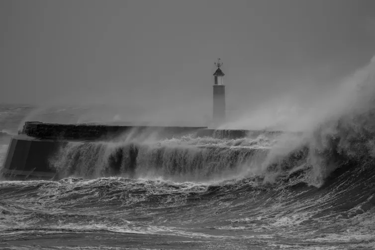 A large wave crashing against a pier.