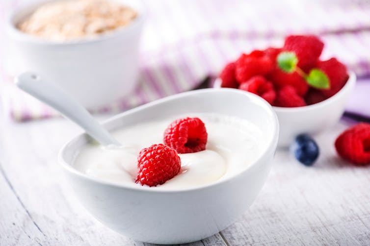 A bowl of plain yoghurt with raspberries on top.