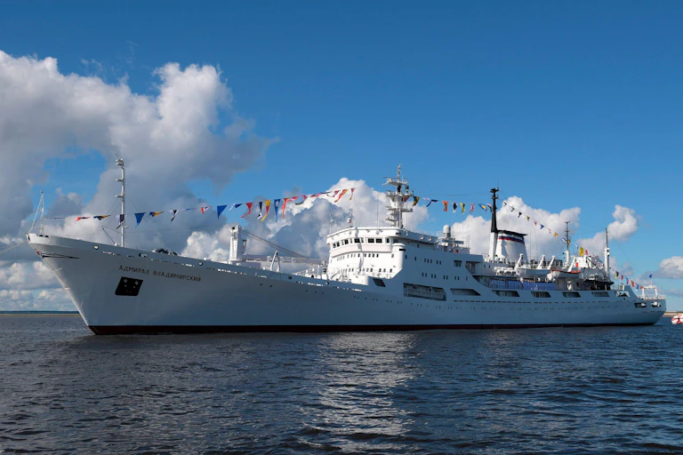 A ship at sea decorated with bunting.