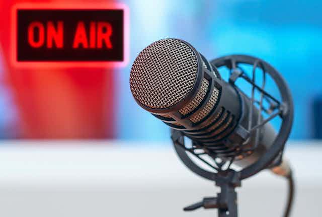 Photo of a radio microphone with a sign in the background that says 'on air' in red