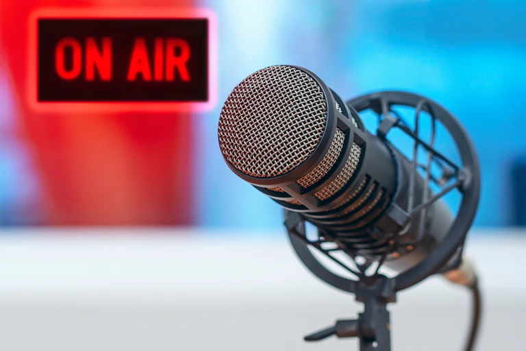 Photo of a radio microphone with a sign in the background that says 'on air' in red
