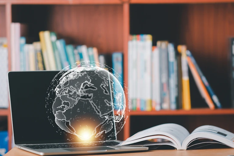 Un ordinateur ouvert devant une bibliothèque avec un globe