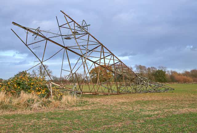 An electricity pylon fallen in a field.