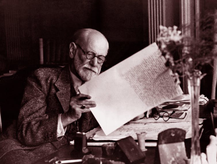 Sigmund Freud holding a large piece of paper.