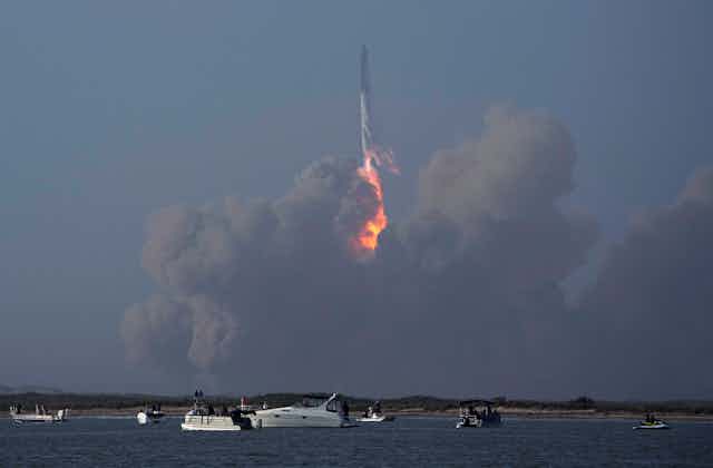 A rocket in the distance with a ball of fire and smoke below it.