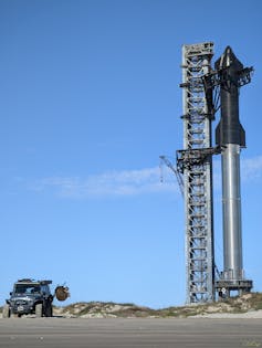 A large rocket standing next to a tower.