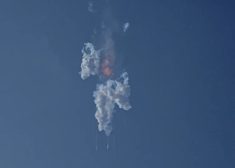 A cloud of fire and smoke in the sky with pieces falling Earthward.