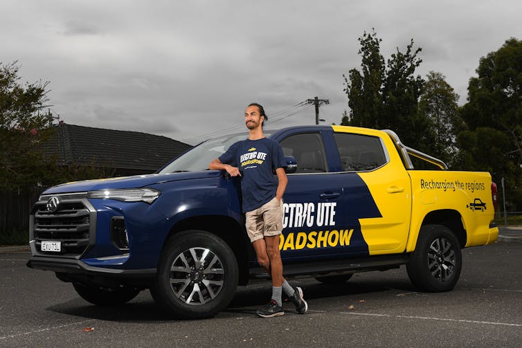 Man stands next to an electric ute with the words'Electric Ute Roadshow' on its side