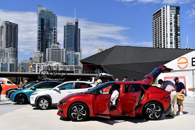 People inspect cars lined up at an electric vehicle expo